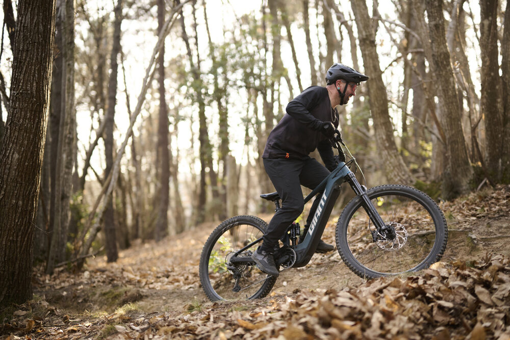 Giant Stance E+ 0 Deep Lake 2027 – ve výjezdu v lese
